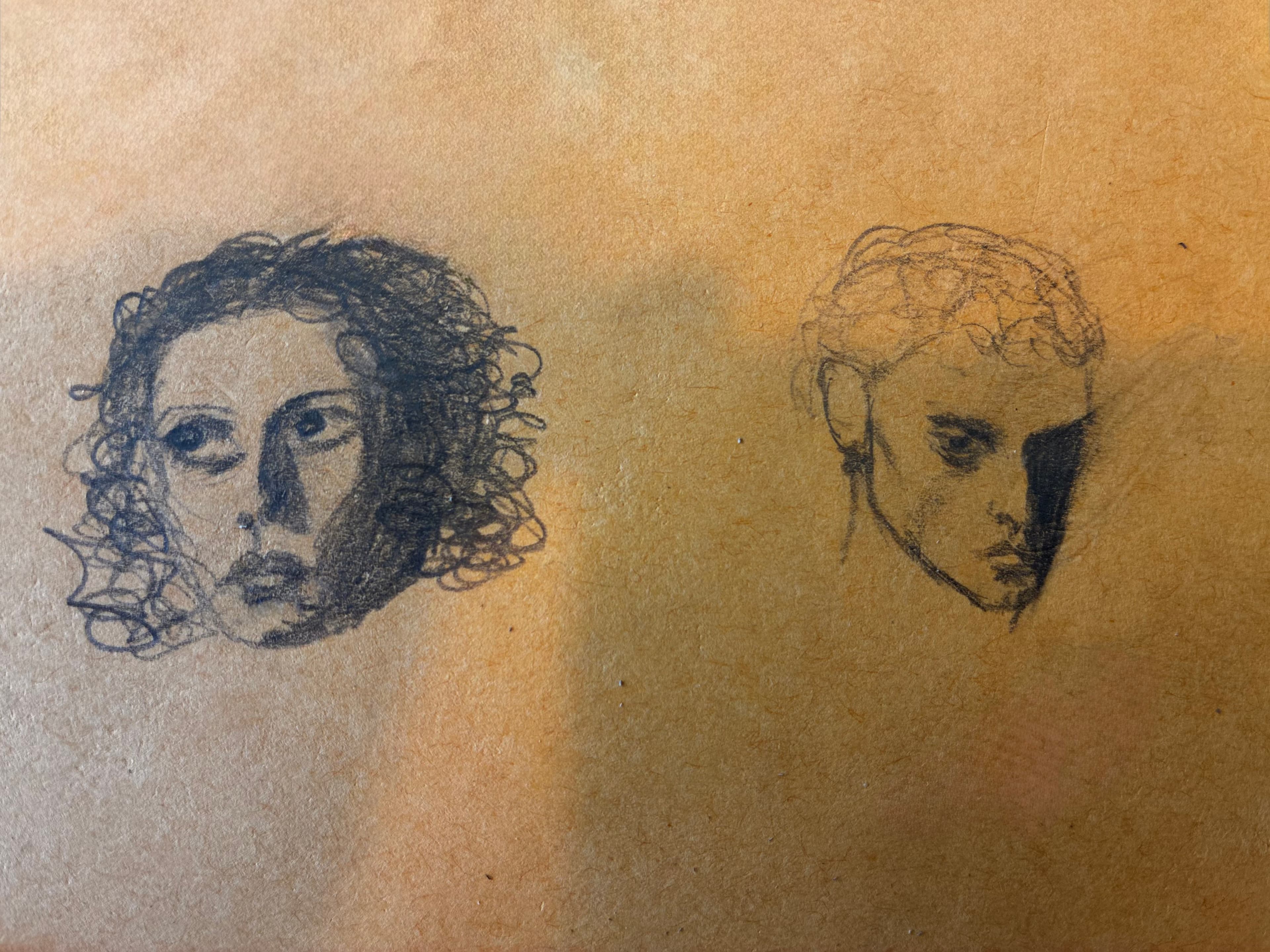 Two pencil sketches of faces on toned paper